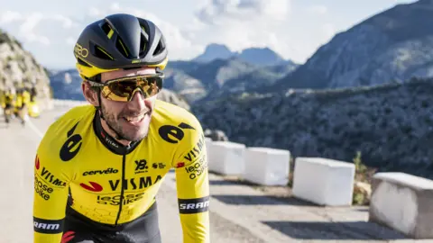 Simon Yates smiling as he rides up a hill