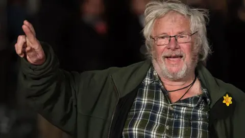 Getty Images Bill Oddie is photographed crossing his fingers and pointing to the sky