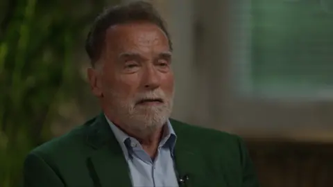 Arnold Schwarzenegger speaking to the BBC, wearing a green suit jacket