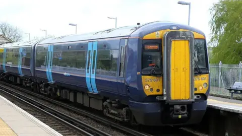 A dark blue and yellow train at a station.