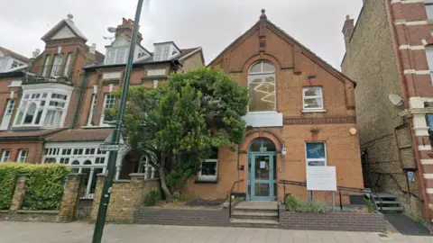 Streetview image of the nursery, a red brick building with a sign outside