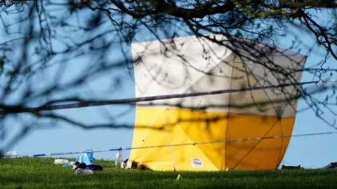 PA Media A yellow and white police forensic tent at the scene at Primrose Hill