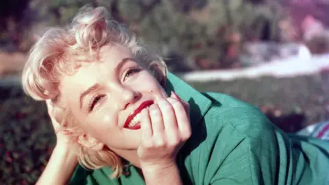 A woman, Marilyn Monroe, wearing a green top.