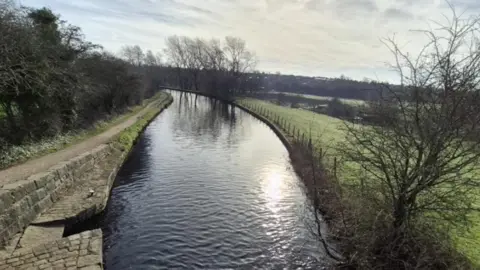 The canal on a clear winter's day with bare trees and fields in the distance