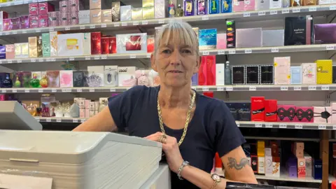 A woman at a shop with fragrances behind her