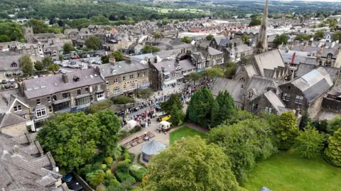 A drone image of Ilkley in West Yorkshire, which was taken on Yorkshire Day as you can see the parade. There are fields, trees and rooftops of the main street 