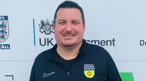 Liam Rooney wearing a Derbyshire FA black jacket