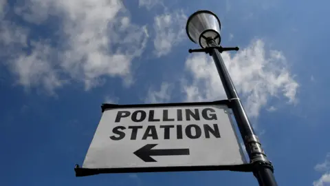Reuters Sign on lamp post reads 'polling station' with a black arrow pointing left