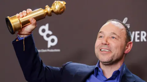 Stephen Graham holding up a Golden Globe