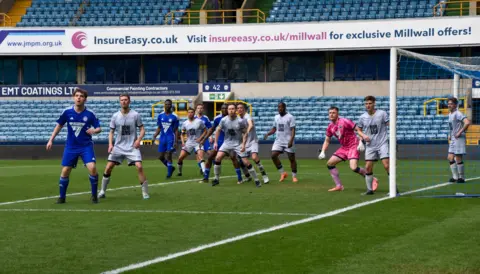 Millwall Romans A group of football players on the pitch mid-game.