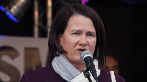 Catherine West speaks into a microphone in 2017.
