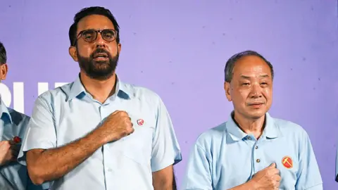 Getty Images Pritam Singh and Low Thia Khiang standing side by side, with their fists raised to their chest