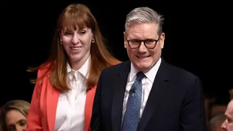 Getty Images Angela Rayner and Sir Keir Starmer smile as they walk through a crowd.