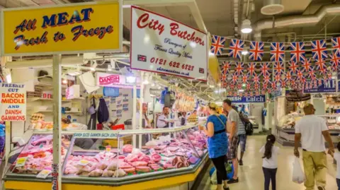 Getty images people look at a color stall on the butcher market. The sign above the stall says all the meat fresh for freezing and another says "city ​​butchers"S