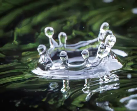 Robin Gladstone Extreme close up of the splashback of a water droplet hitting a body of water