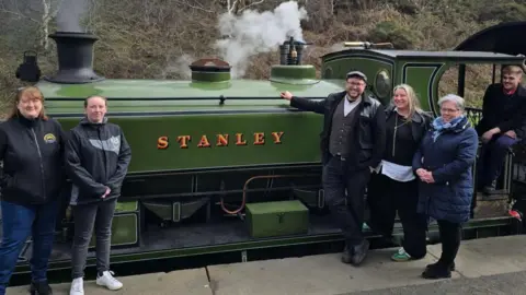 Handout Representatives of organisations leading Stanley's Town of Culture bid stand in front of a green steam train with the word Stanley printed on the side.