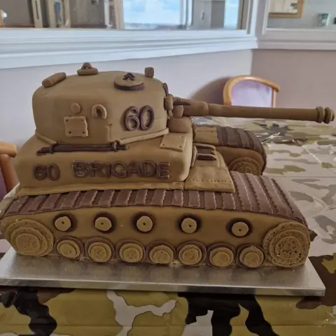 Family A cake in the shape of a tank with the number 60 on it