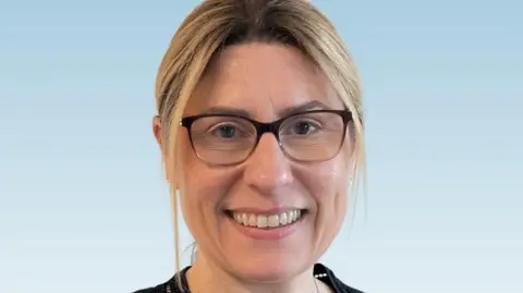 Mid and South Essex NHS Foundation Trust A woman with framed glasses smiling with a light blue background
