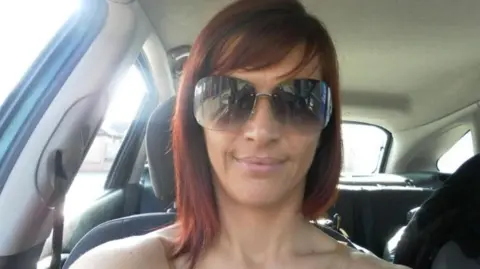 Brooklyn Bryan A woman with red shoulder length hair and large sunglasses looks at the camera for a selfie in the passenger seat of a car