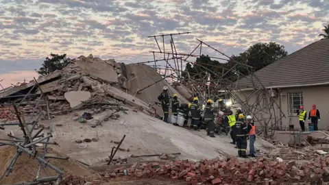 Rescue workers are seen at the scene of a collapsed building in George on May 7, 2024.
