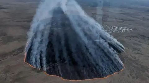 Devon and Somerset Fire and Rescue Service An aerial image showing open plains with a large fire burning through the landscape.