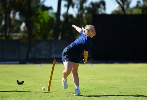 Getty Images Niamh Muir in a dark blue top and skirt bowls a cricket ball on a perfect flat grass pitch