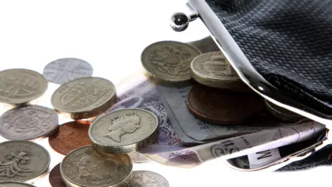 BBC A black purse with the clasp open and money spilling out.