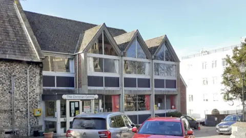 Sue Jamieson A picture of The Christian Centre in Dorking, Surrey. The centre has two storeys and has three triangular features on the front. 'The Christian Centre' is written above the entrance door, which is white.