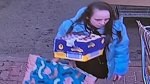 A blurry CCTC image of a woman carrying a box of chocolate.