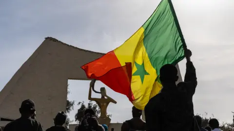 Activists, one holding a Senegalese flag, take part in a march against homosexuality in Dakar, Senegal, 06 March 2026