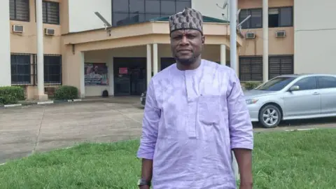 Courtesy of Hassan Ajibola Hassan Ajibola, the head of a teaching union in Oyo state, stands in front of a municipal building.
