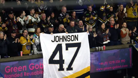 PA Media A large white banner held up by a number of fans in a stadium