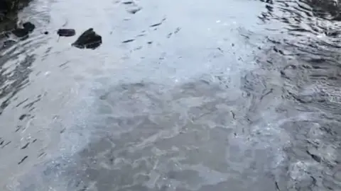 Fuel spill in a river in Perthshire, the water looks oily with a white film on it in places