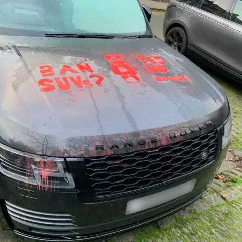 Paint washing off slightly on a Range Rover but the red messages can still be clearly read. 'Ban SUVs' and 'Yes No Not sure'.