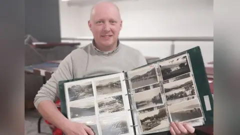 Auctioneer with postcards