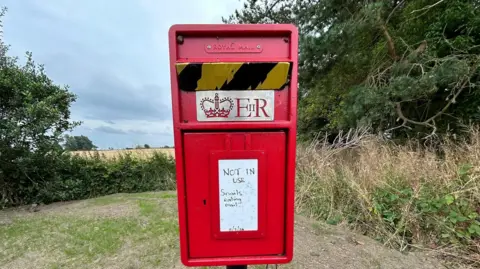 Guy Renner-Thompson A post box with a sign on it saying 'NOT IN USE - snails eating mail' - with the date of 11 July 2024 on it 