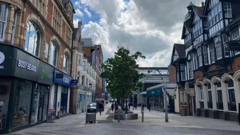 A pedestrianised town centre with shops and trees