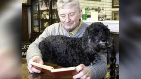 Potters Saleroom Paul Potter with his dog Henry looking at the autograph book