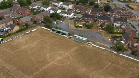 An aerial photograph taken with a drone of a dry football pitch and cricket in Llay, Britain, 27 July 2026.