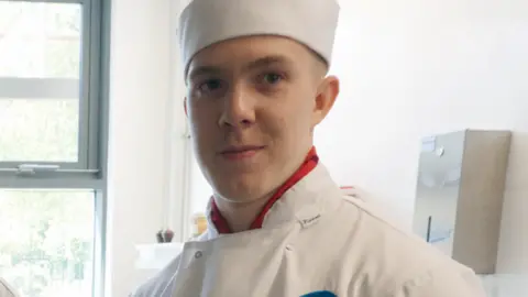 Family photograph  A caput  and shoulders changeable  of Joe dressed successful  achromatic  catering covering  and hat. He has a reddish  garment  connected  underneath