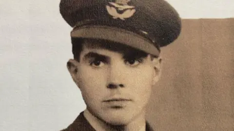 An old sepia colour photo of a young Stanley Booker in his RAF uniform. His peaked cap is at a slight angle and bears the RAF emblem.