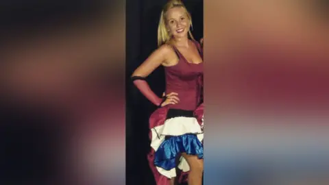 Supplied Aimee is standing in the middle with her arm on her hip. She has long blonde hair and is wearing a red top, and a white and blue skirt.