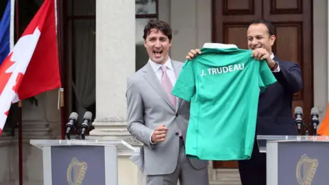 PAUL FAITH/AFP via Getty Images) Former Canadian Prime Minister Justin Trudeau (L) is presented with an Ireland rugby union shirt and a pair of socks, by Ireland's Prime Minister Leo Varadkar (R) at Farmleigh House in Dublin on July 4, 2017.