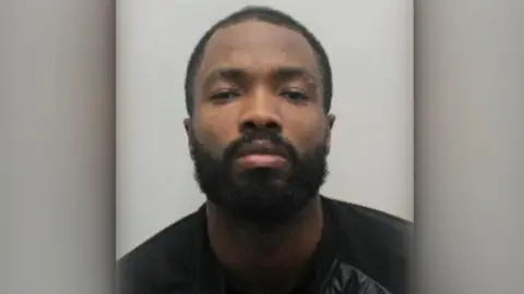 Metropolitan Police Custody photo of Javon Riley, who has a beard and moustache.