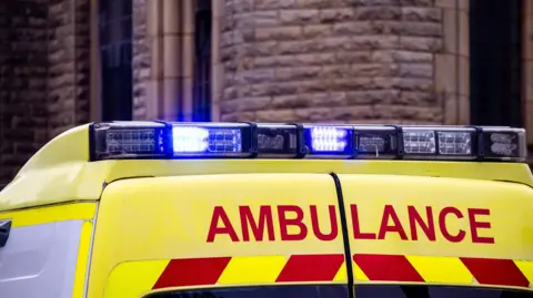 A stock photo of an ambulance with flashing blue lights.