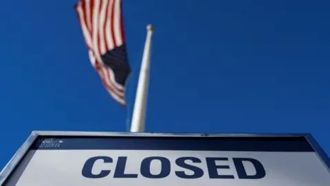 Getty Images Sign saying 'CLOSED' in front of USA flag