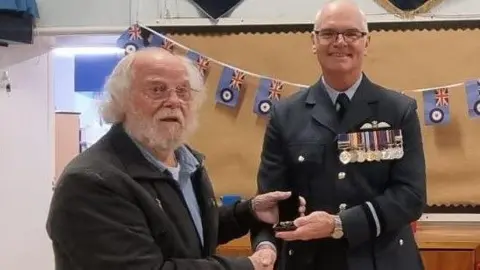 Frank Dinsdale is presented with the medal for his services