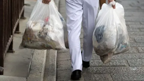 Getty Images A man carrying garbage bags 