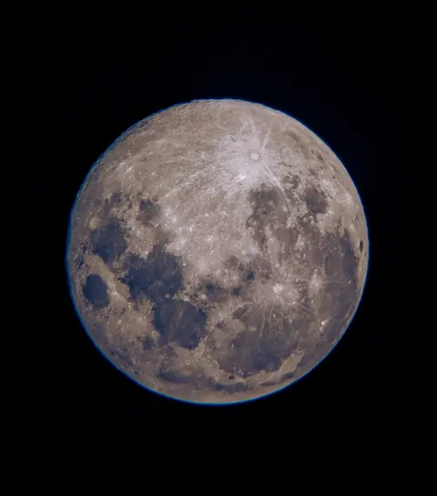 Katey Munn A close-up picture of a silvery moon with dark patches on a pitch black background