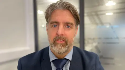 Adam Rose is wearing a suit and tie